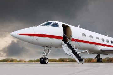 Ambulans uçağın pistte hazır beklediği bir sahne, arka planda sağlık personeli ve sedye görülüyor.