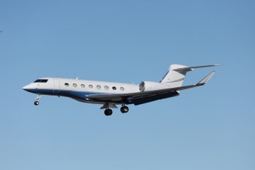 Asya kıtasında farklı şehirler arasında uçan özel jet, aşağıda modern şehir manzaraları.