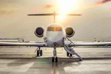 Özel bir jetin yanında valiziyle bekleyen bir yolcu, uygun fiyatlı jet kiralama konsepti.