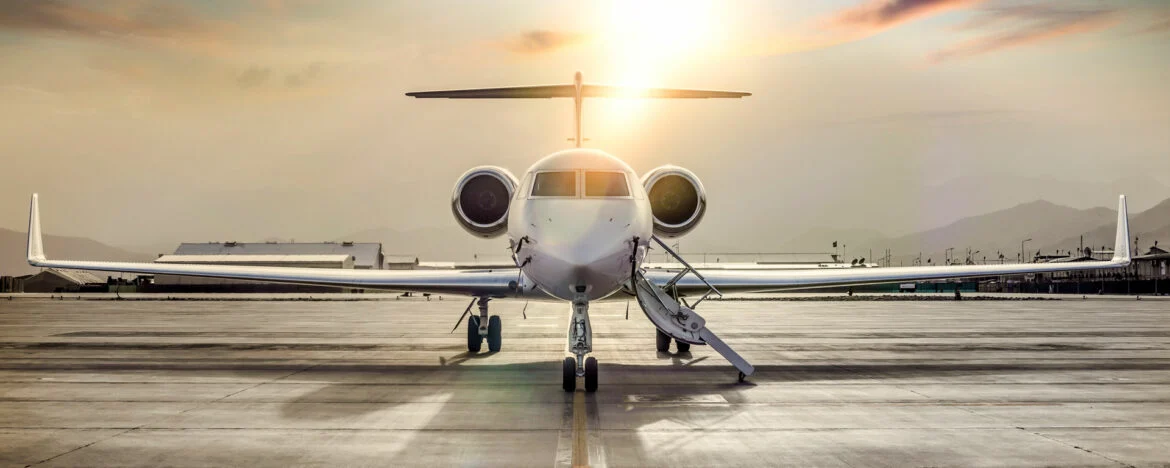 Özel bir jetin yanında valiziyle bekleyen bir yolcu, uygun fiyatlı jet kiralama konsepti.