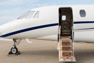 Avrupa’ya doğru havalanan özel bir jet ve terminalde elinde valiziyle bekleyen bir yolcu.