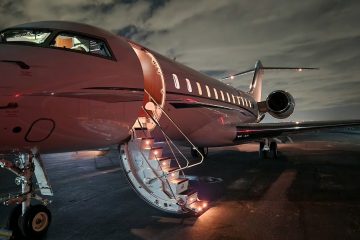 Özel jetin yanında valizleriyle bekleyen takım elbiseli iş insanları, arka planda modern bir havalimanı.