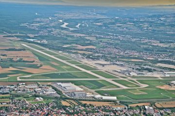 Basel Mulhouse Freiburg Havalimanı’nda (MLH) apron üzerinde park halinde, yolcularını bekleyen modern bir özel jet ve arka planda terminal binası.