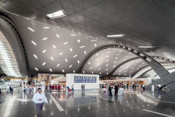 Doha Hamad Uluslararası Havalimanı’nda (DOH) geniş terminal binası, yolcu köprülerine yanaşmış uçaklar ve modern apron manzarası