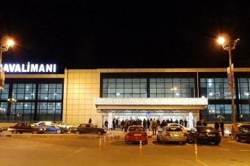 Kıbrıs’ın Lefkoşa yakınlarında yer alan Ercan Havalimanı terminal binası, önünde park etmiş yolcu uçakları, yolcu indiren araçlar ve giriş kapısında hareketlilikle birlikte görülüyor.
