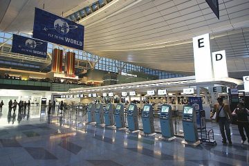 Tokyo Haneda Havalimanı’nda gece ışıkları altında park etmiş modern bir özel jet ve terminal manzarası.