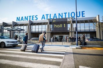 Nantes Havalimanı’nda (NTE) terminal binası önünde park etmiş yolcu uçağı ve apron üzerinde hareket eden yolcular
