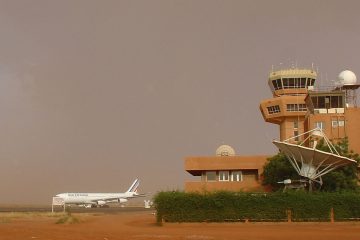 Nijer Niamey Havalimanı’nda (NIM) terminal binası önünde park etmiş yolcu uçağı ve çevresinde sıcak, kurak Afrika manzarası